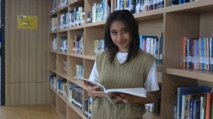 seorang mahasiswi sedang membaca di perpustakaan UBM