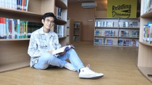 seorang mahasiswa sedang membaca di perpustakaan UBM Ancol